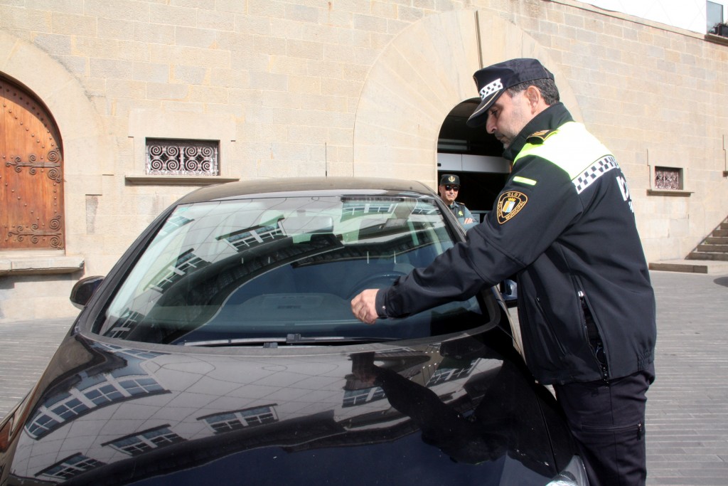 El cap de la Policia Local d'Olot, Igansi López, multant un vehicle no logotipat de la Guàrdia Civil mal aparcat davant l'ajuntament, sota la mirada d'un agent del cos, aquest 21 d'octubre. (Horitzontal)