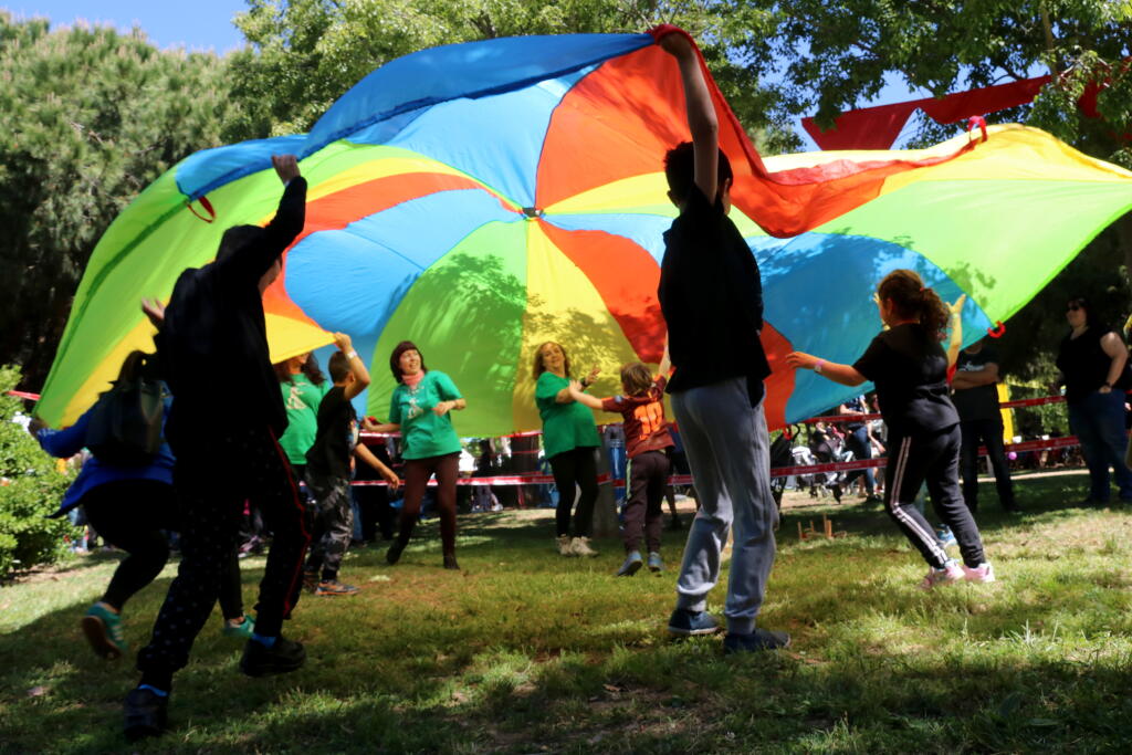 Grup de nens jugant sota un llençol de colors a la Festa Esplai.