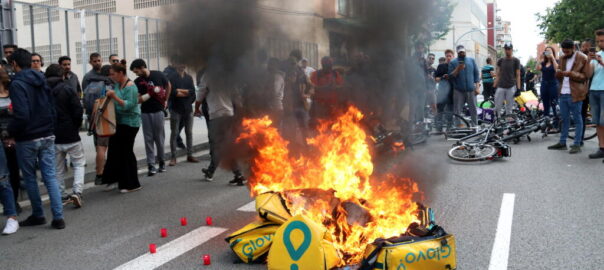 Diversos cistells de Glovo cremant davant d'una de les seus de l'empresa a Barcelona, en una protesta d'ahir