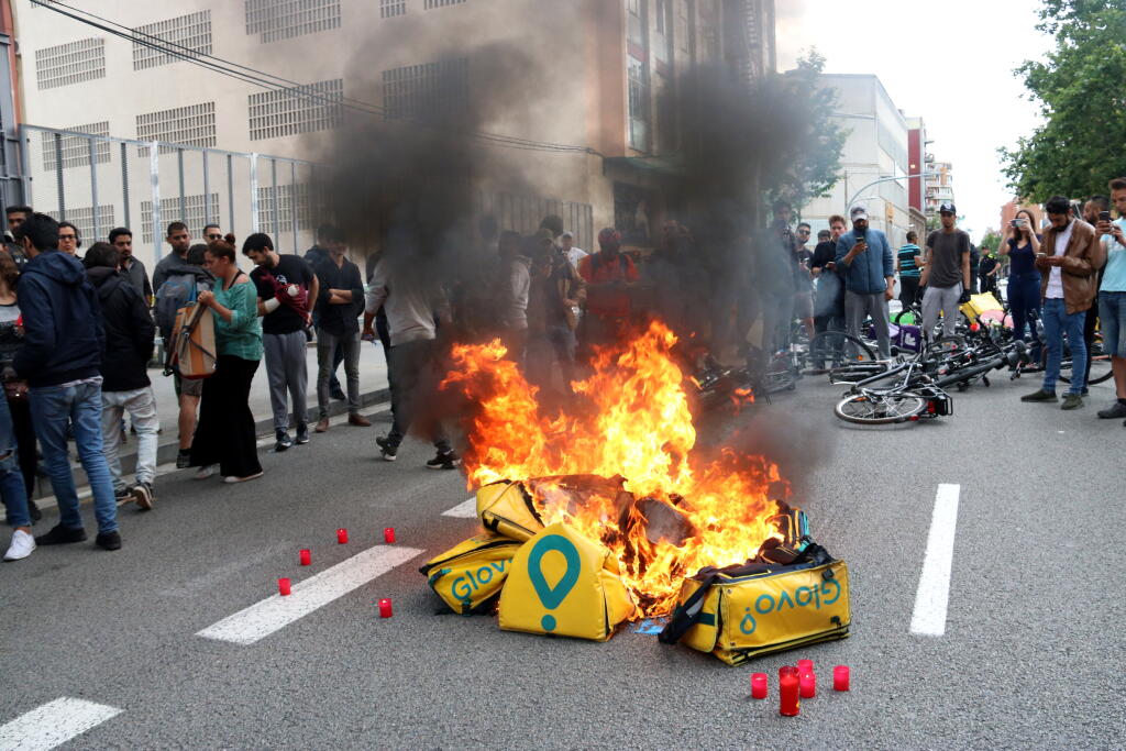 Diversos cistells de Glovo cremant davant d'una de les seus de l'empresa a Barcelona, en una protesta d'ahir