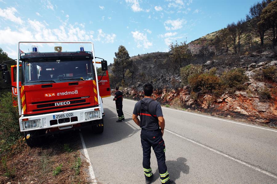 Diversos bombers vigilen la carretera que uneix La Llancuna amb Lorxa, tallada a causa de l'incendi que afecta La Vall de Gallinera. Fotografia: EFE/Natxo Francés
