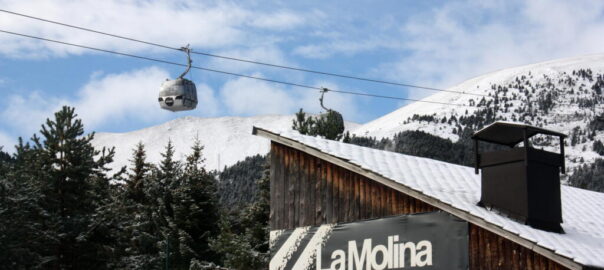 Pla obert d'un cartell indicatiu de l'estació de La Molina col·locat a l'exterior d'un edifici.