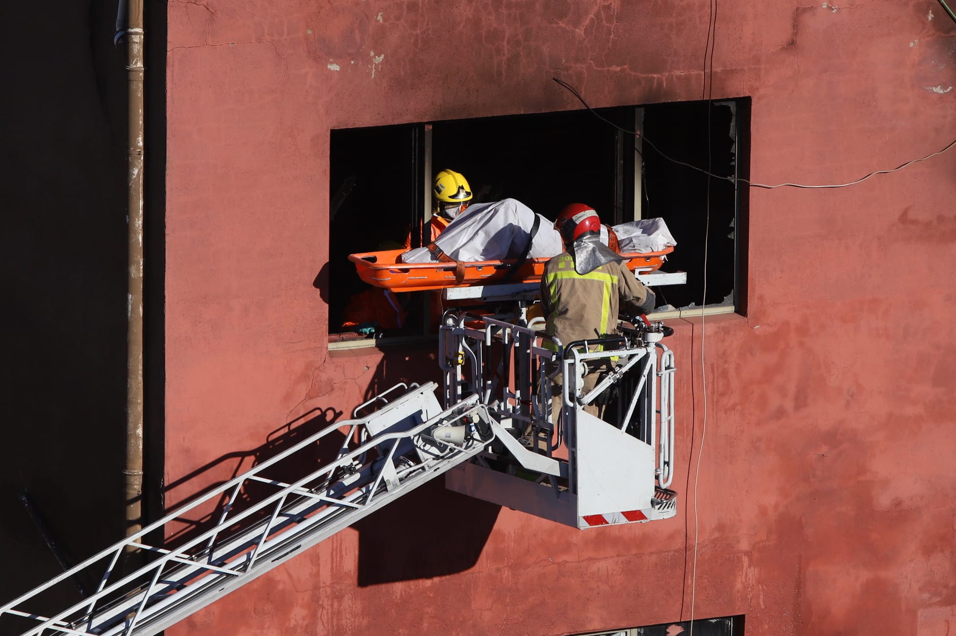 Els bombers retiren un dels cossos de l'interior de la nau incendiada (fotografia: Albert Salamé)