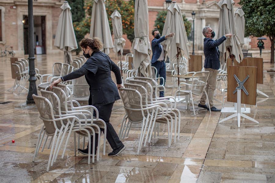 Treballadors d'un bar arrepleguen la terrassa el primer dia del tancament de la restauració a les 17h al País Valencià