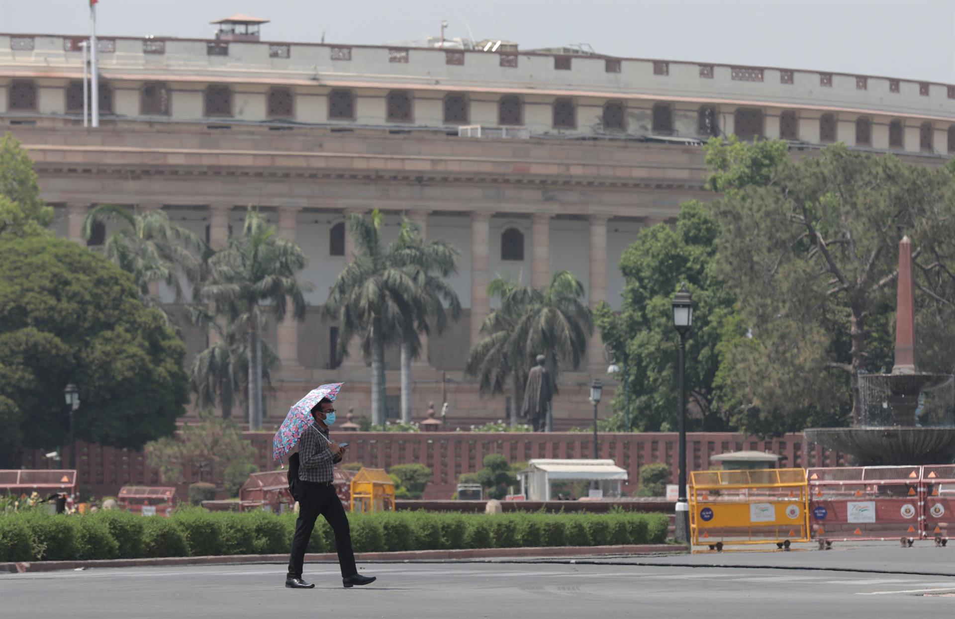Un home es protegeix de la calor a Nova Delhi amb un para-sol. Fotografia: Rajat Gupta/EFE.