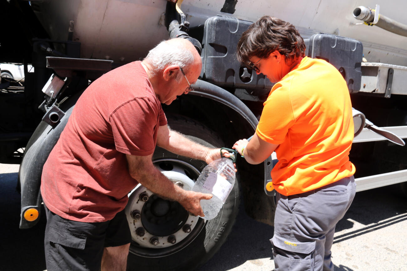 Un veí de Sarroca de Lleida omple garrafes d'aigua potable del camió cisterna