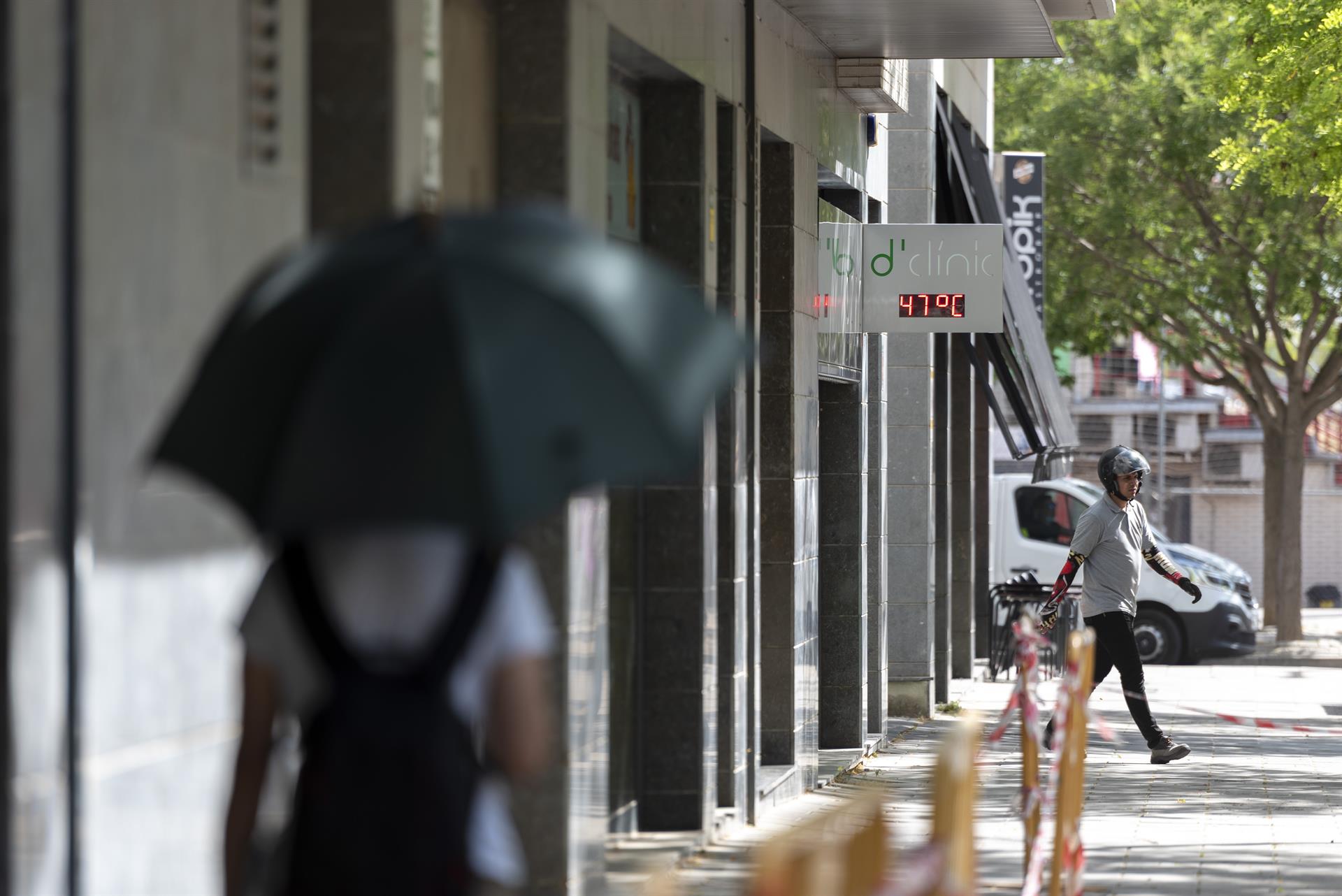 Una dona caminant per Lleida, dimecres passat, davant un termòmetre que marca 47 graus (fotografia: Ramon Gabriel).