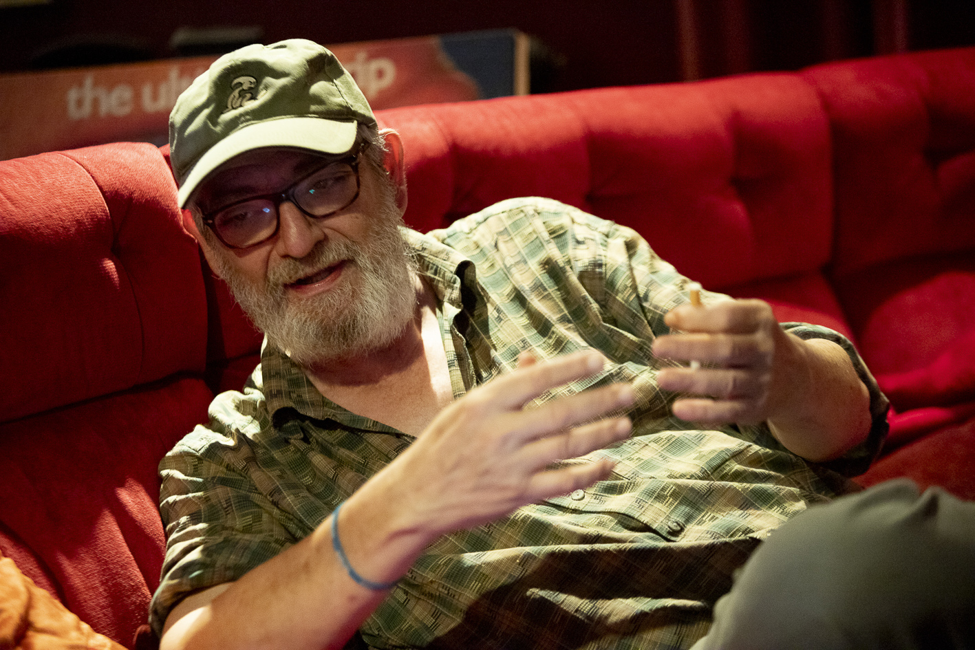 Manuel Huerga, al sofà vermell de vuit places que té a casa seva, davant la pantalla per a veure cinema que hi té instal·lada (fotografia: Albert Salamé)