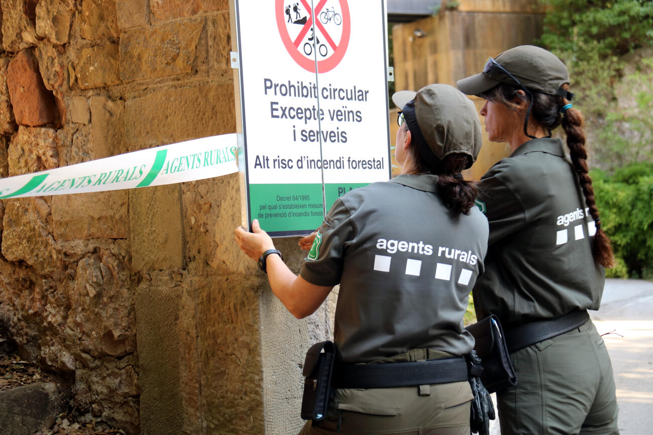 Imatge d'arxiu de dues agents rurals mentre instal·len el cartell de prohibició d'accedir al Parc Natural de Montserrat (fotografia: ACN).