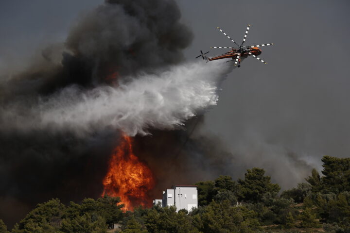 Un helicòpter intentant d'apagar l'incendi (Fotografia: EFE/EPA/Yannis Kolesidis)
