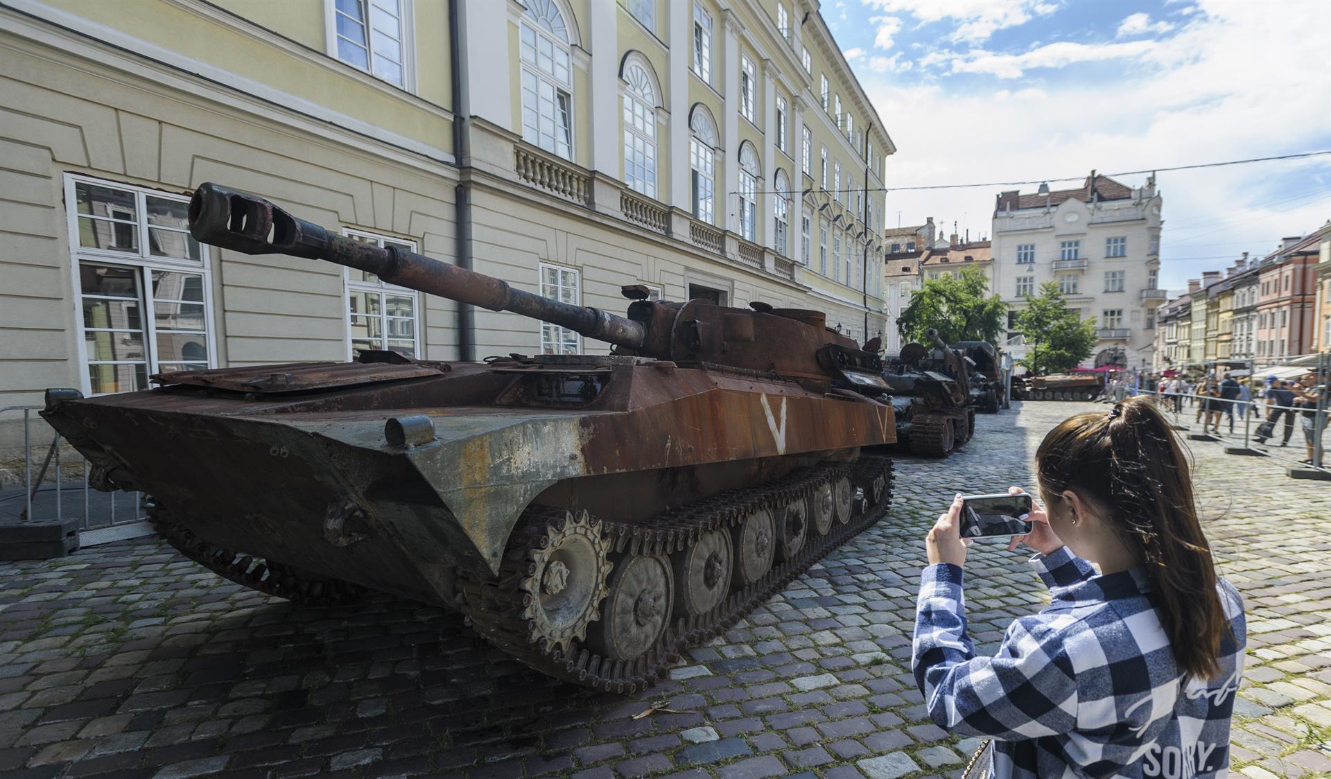 Una dona fotografia un tanc rus destruït, en una exposició que s'ha fet al carrer de Lviv el 10 d'agost de 2022 (fotografia: Mykola Tys/EPA/EFE).