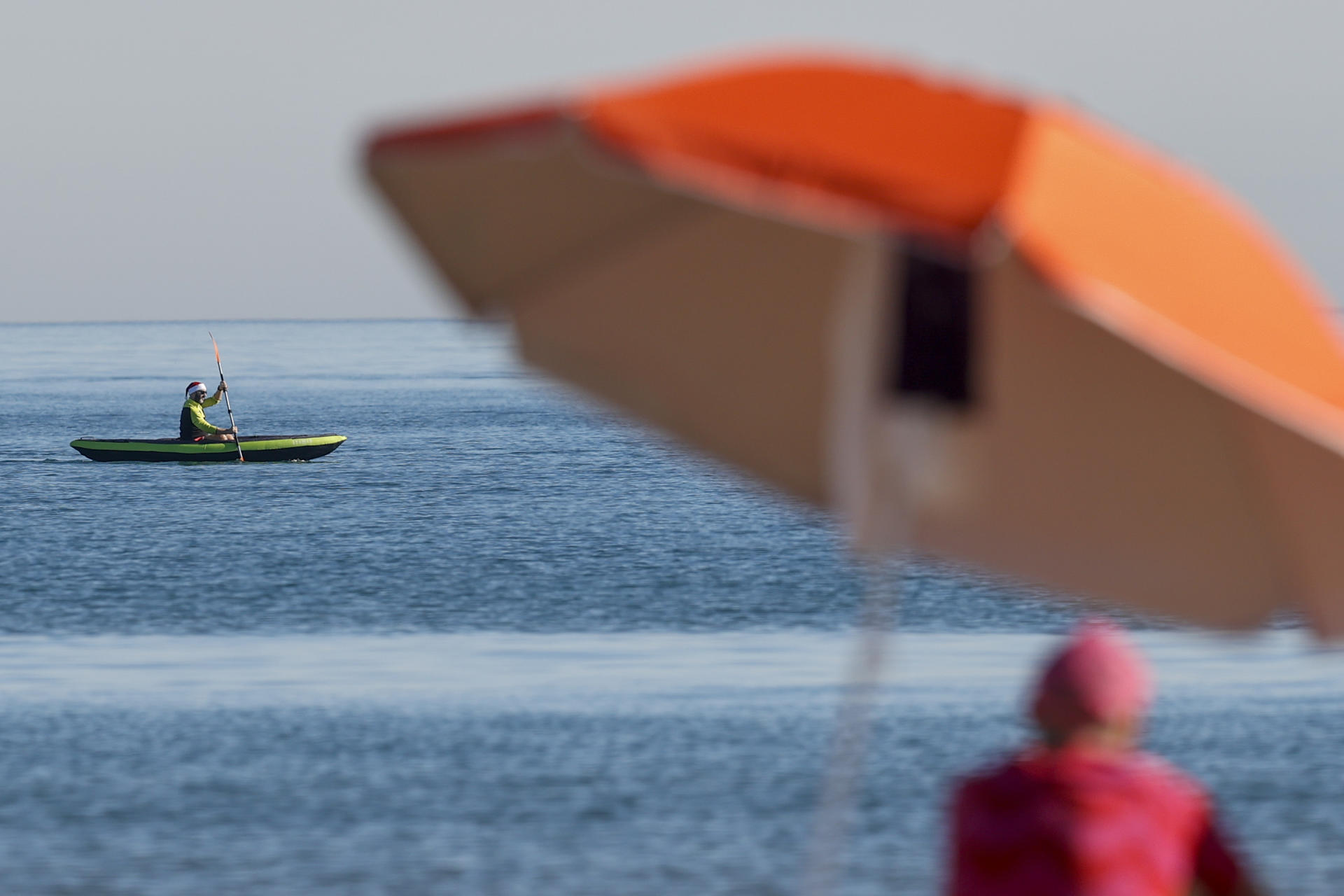 Un home amb barret de Pare Noel rema en caiac a la platja de la Malva-rosa (València) (fotografia: EFE/Kai Försterling).