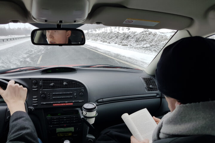 Carles Puigdemont (dreta) llegint un llibre, i Janne Riitakorpi, al volant, al seu pas per Finlàndia dins el Saab vermell que van fer servir (Foto: Jami Matamala)