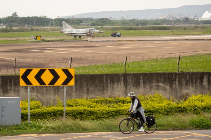 Un home en bicicleta amb un avió militar de Taiwan al fons. Fotografia: EFE/EPA/RITCHIE B. TONGO