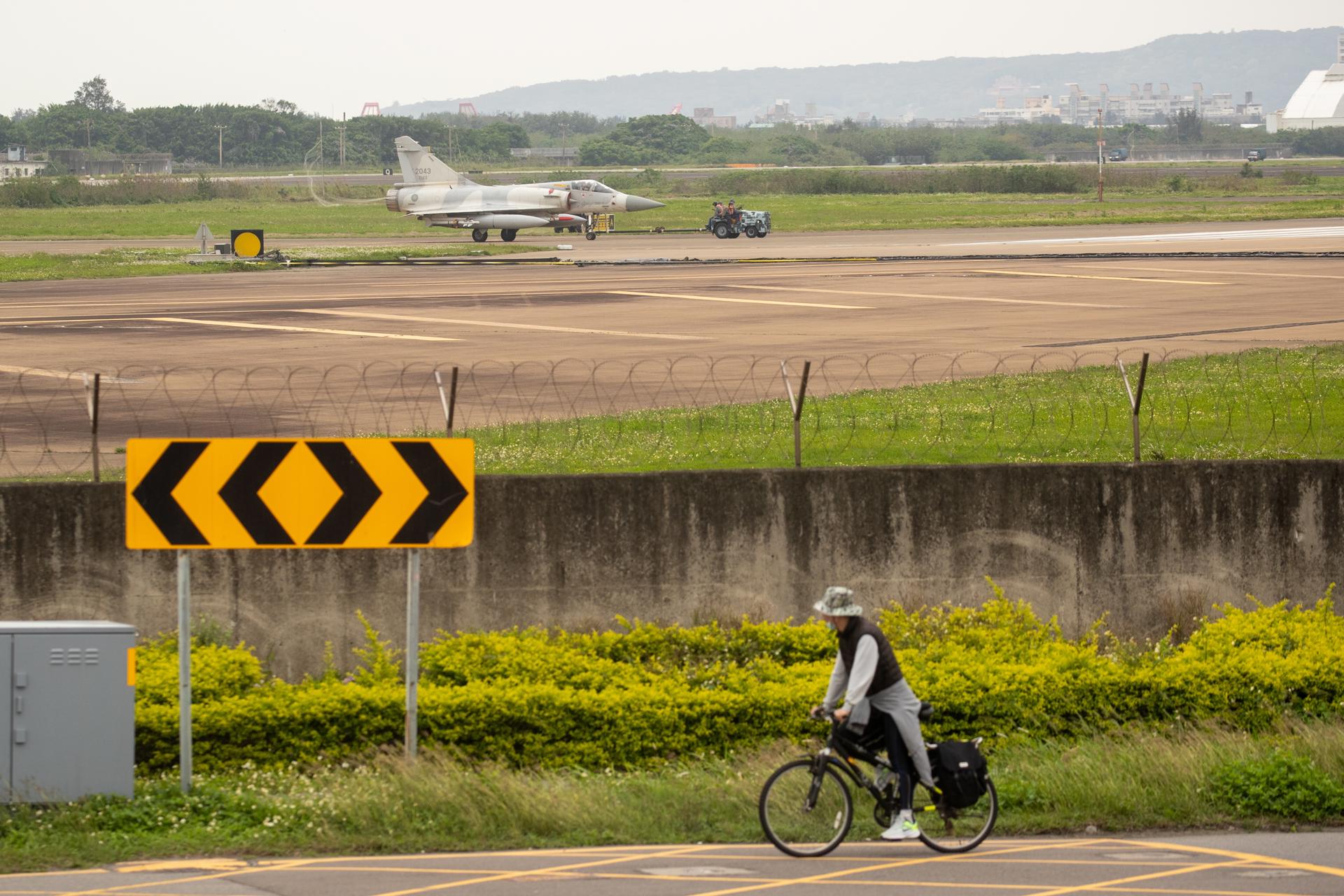 Un home en bicicleta amb un avió militar de Taiwan al fons. Fotografia: EFE/EPA/RITCHIE B. TONGO