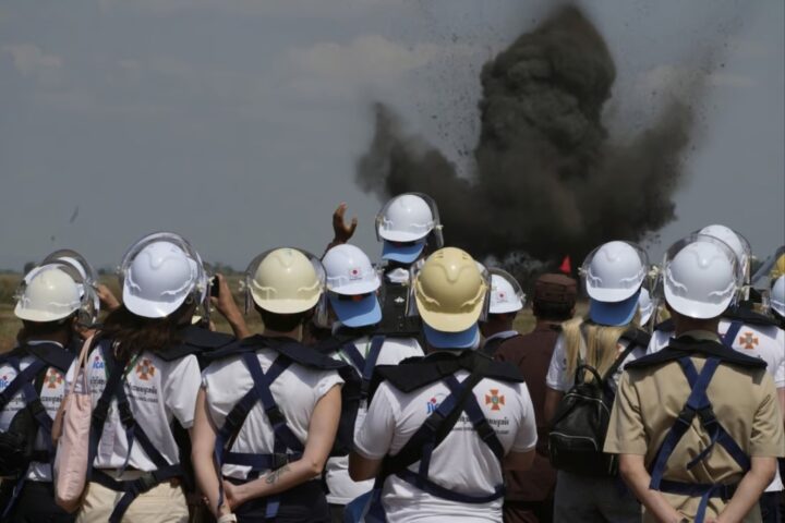 Desminadors ucraïnesos observant una explosió controlada en un camp de batalla de Cambotja. Gener del 2023 (fotografia: AFP).