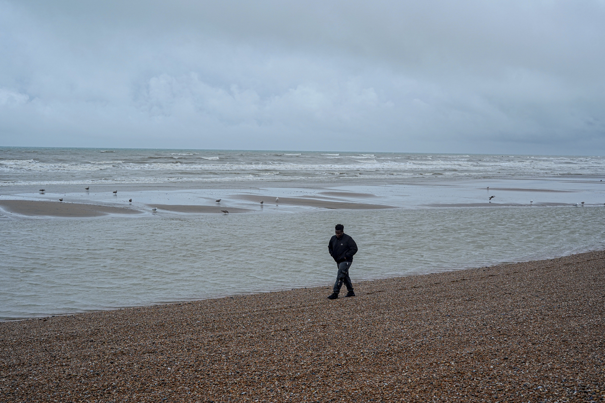 Bidias, un sol·licitant d'asil de 32 anys de Camerun, camina pel platja a Hastings.(Fotografia per a The Washington Post de James Forde.)