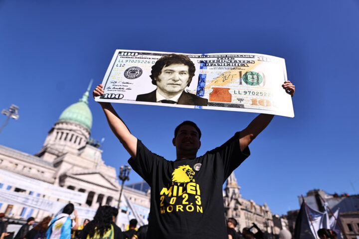 Un manifestant a l'Argentina ensenya un cartell que reprodueix un dòlar amb la cara de Milei. (Fotografia de Juan Ignacio Roncoroni)