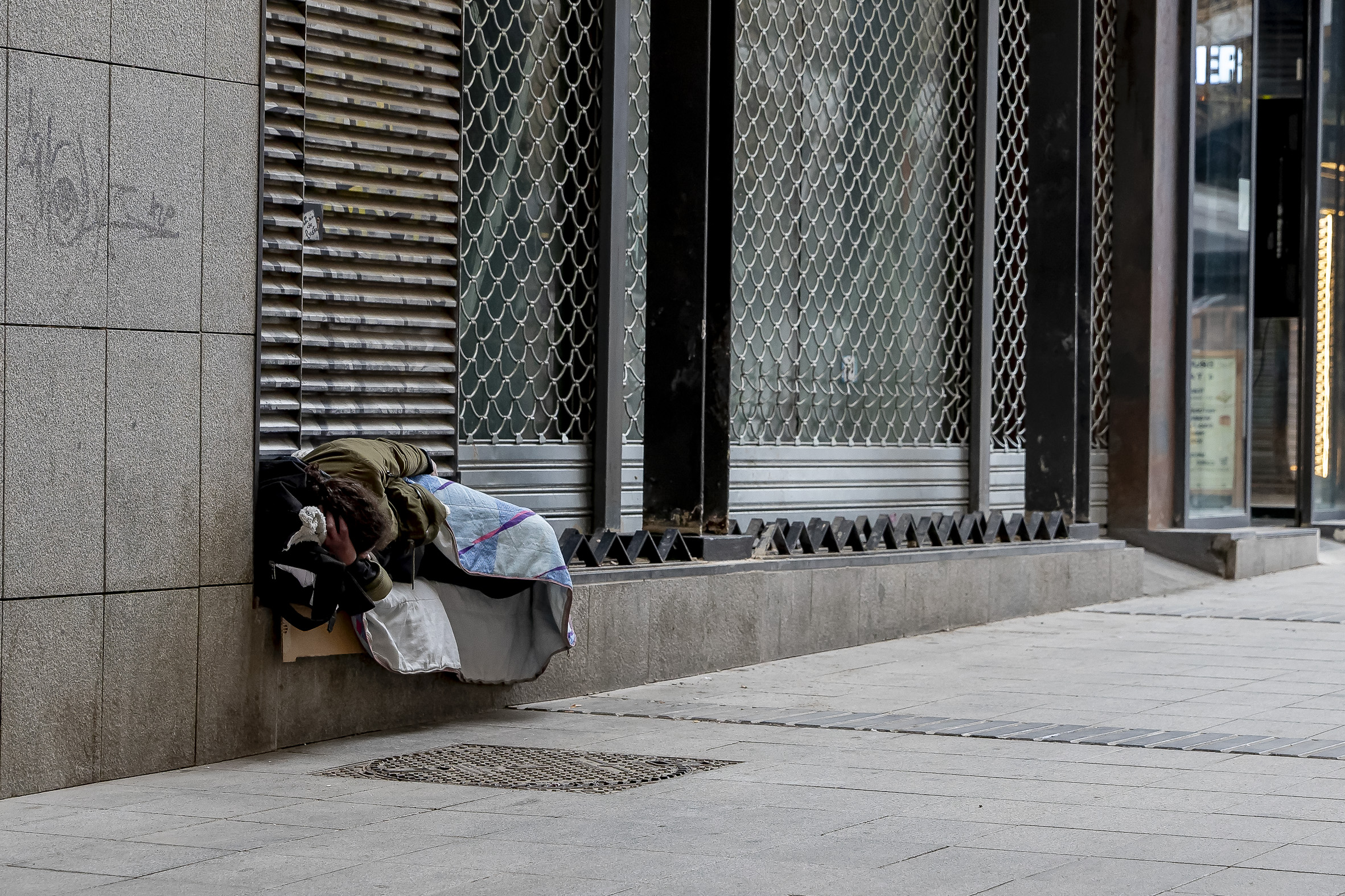 Un sense-sostre dormint al carrer a Barcelona, en un espai en què ja s'ha col·locat un element d'arquitectura hostil (fotografia: Albert Salamé).