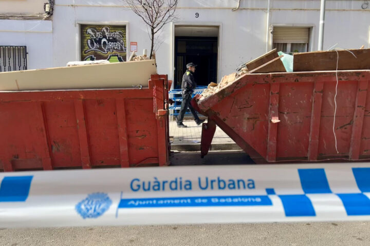 El portal de l'edifici sinistrat del carrer Canigó de Badalona, amb contenidors de runa al davant (fotografia: ACN / Jordi Pujolar).