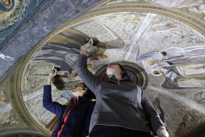 Dues restauradores treballen en la neteja dels frescos de Josep Obiols a les avantsales de Cambril de la Mare de Déu de Montserrat (fotografia: ACN / Mar Martí).
