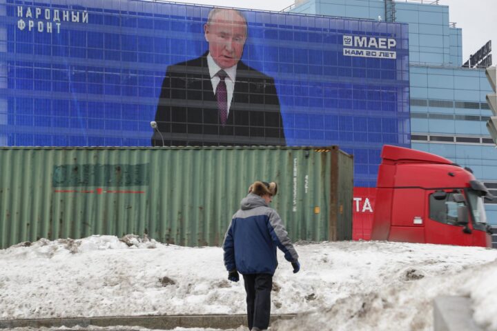 Un home camina davant d'una de les pantalles des d'on es retransmet el discurs de Putin a la nació. Moscou. (fotografia: EFE/EPA/Maxim Xipenkov)