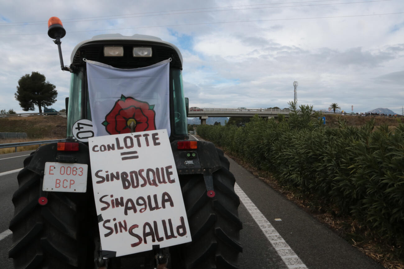 Un tractor, al tall de l'AP-7, mostra una pancarta de protesta contra el projecte de Lotte Energy Materials