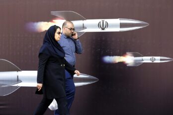 Una parella passa davant d'una immensa pancarta amb fotos de míssils, a Teheran el 19 d'abril del 2024. (Fotografia d'Abedin Taherkenareh)