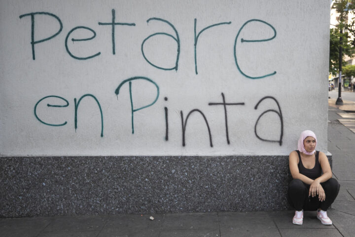 Una manifestant descansa davant una pintada de suport al barri de Petare. (Fotografia de Ronald Peña)