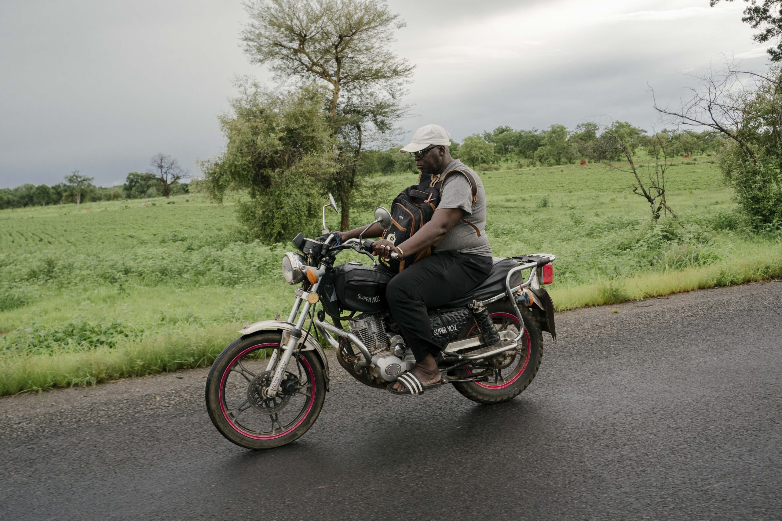 Momodou Keita, un home de cinquanta-un anys, pare de cinc fills i detectiu informal en la lluita contra la mutilació genital femenina a Gàmbia, patrulla amb la seva moto anomenada 