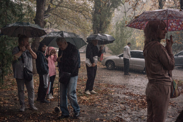 La gent fa cua sota la pluja torrencial per rebre paquets de menjar. Les tempestes són un dels pocs moments en què els residents de Kherson poden confiar que no es convertiran en el blanc dels atacs russos (fotografia: Alice Martins/The Washington Post).