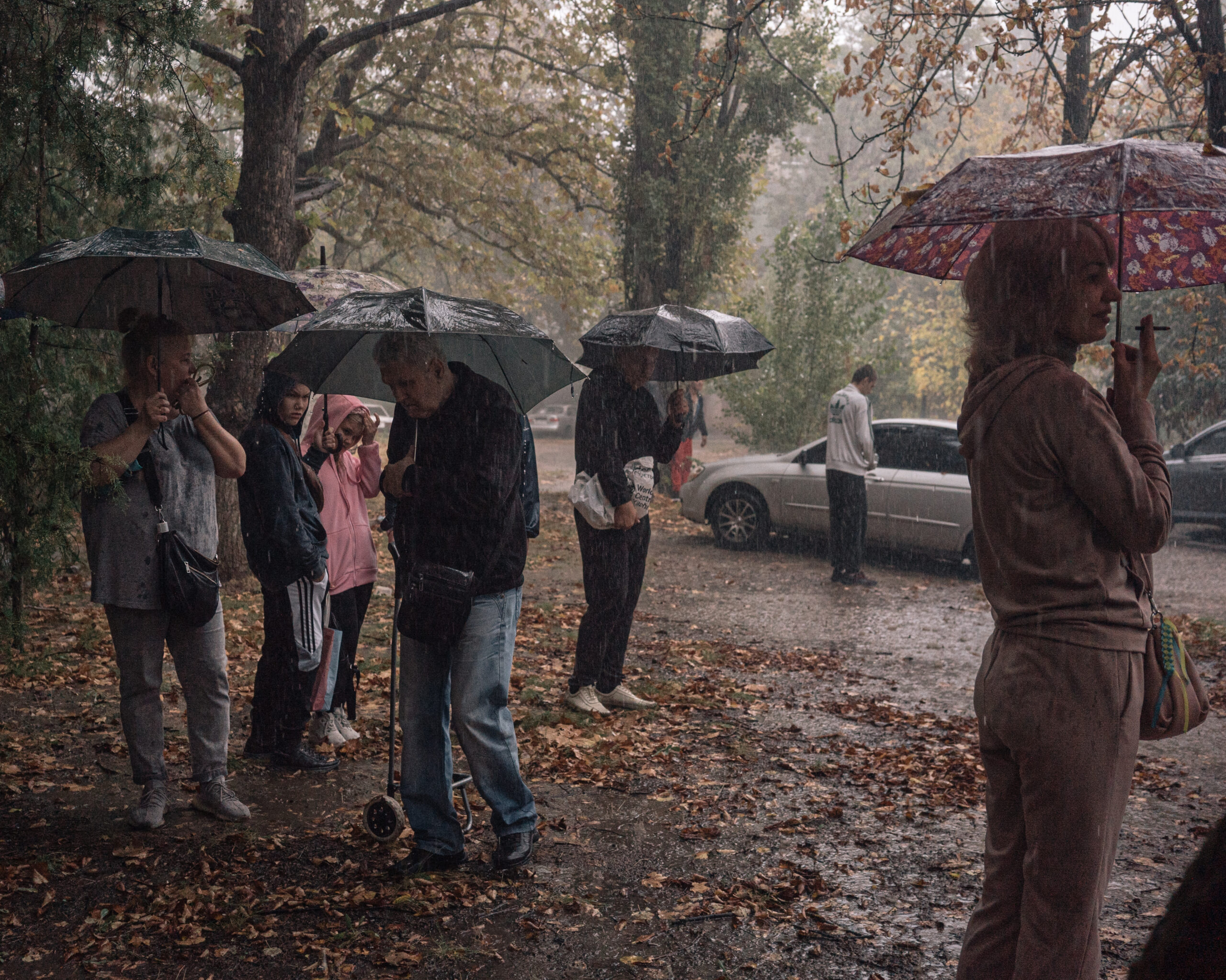 La gent fa cua sota la pluja torrencial per rebre paquets de menjar. Les tempestes són un dels pocs moments en què els residents de Kherson poden confiar que no es convertiran en el blanc dels atacs russos (fotografia: Alice Martins/The Washington Post).