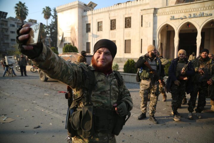 Un grup de rebels es fa fotografies davant un edifici del govern capturat ahir a la ciutat de Hama (fotografia: Bilal Al-Hammoud).