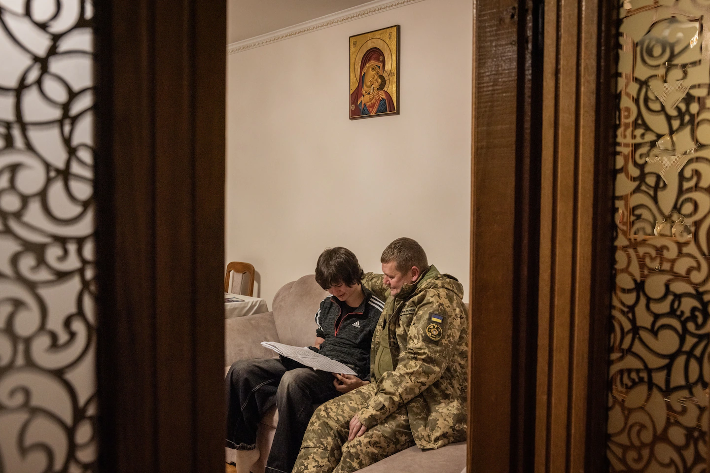 En Nazar i el seu pare, n'Andrii, seuen al sofà de casa (fotografia: Ed Ram/The Washington Post).