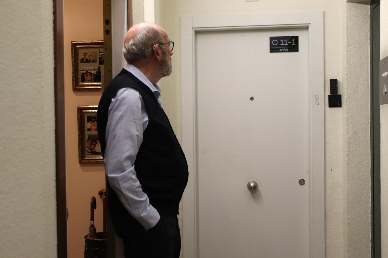 L'Enrique es mira la porta del costat, on hi ha un apartament turístic (fotografia: ACN / Blanca Blay).