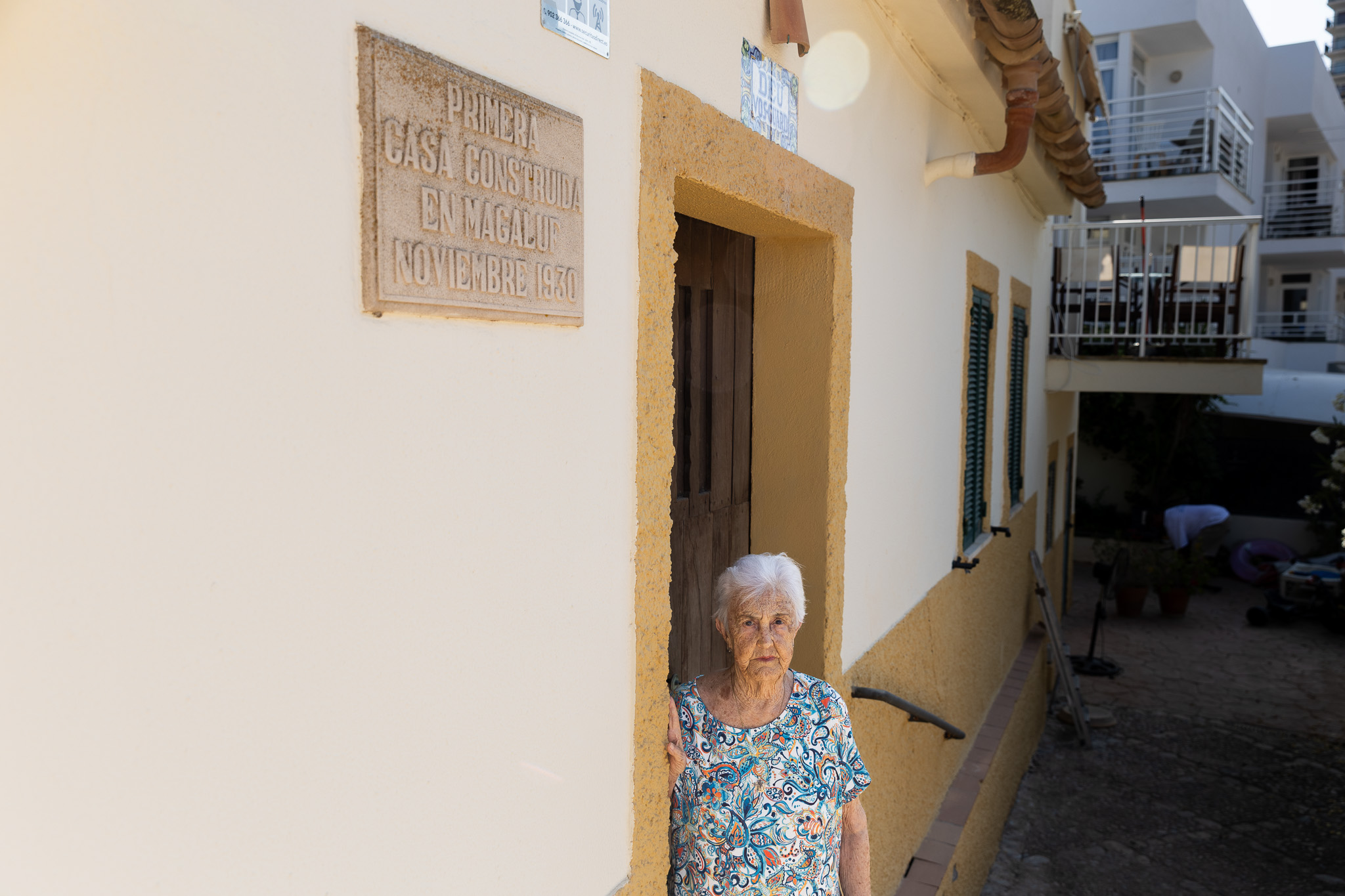 Catalina Feliu, davall la placa que diu que és la primera casa construïda a Magaluf (fotografia: Martí Gelabert).