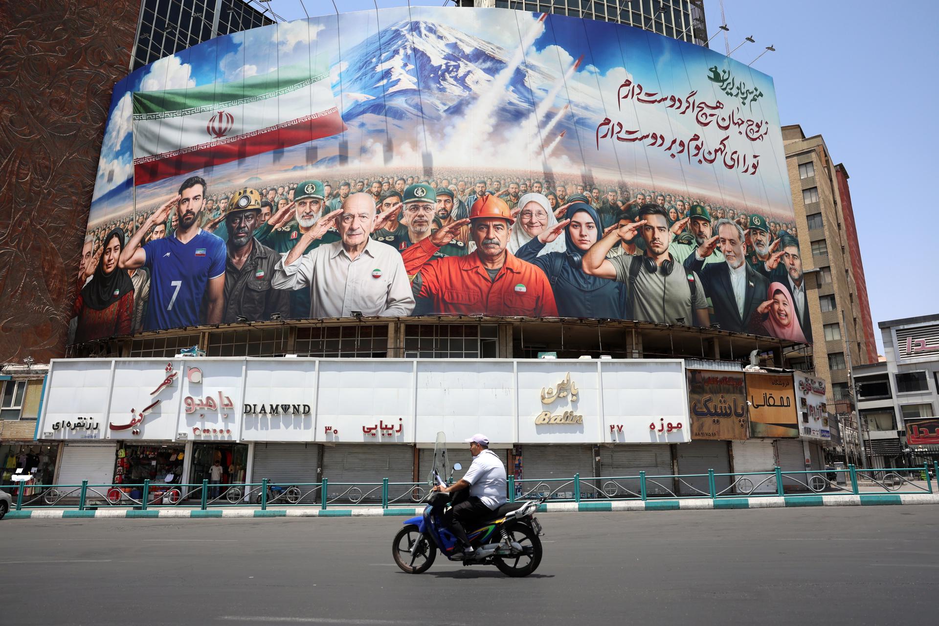 Un home passa per davant d'una tanca publicitària en què es llegeix l'eslògan 