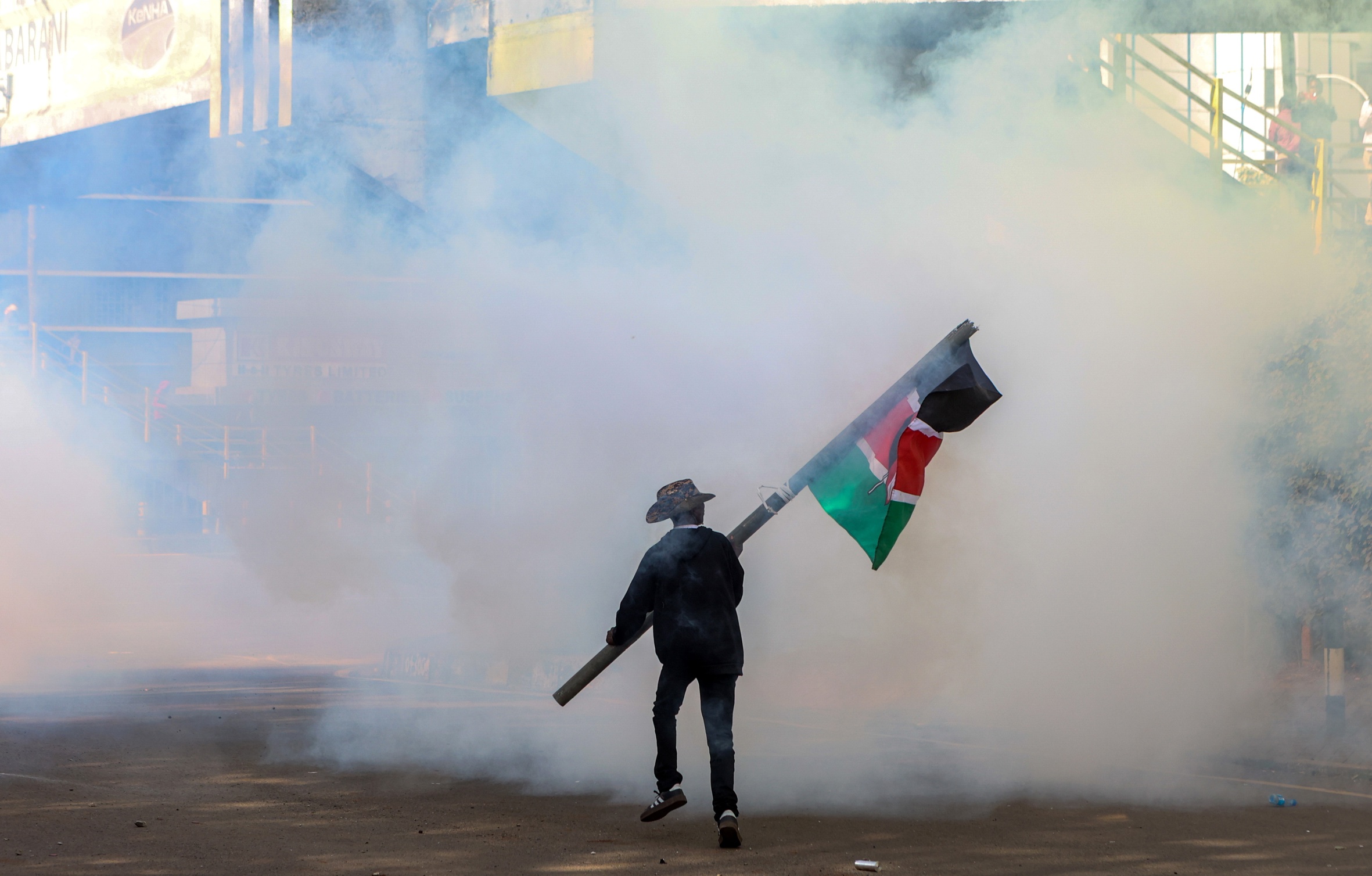 Un manifestant oneja una bandera de Kènia mentre prova d'evitar el gas lacrimogen durant una manifestació a la capital del país, Nairobi, la setmana passada (fotografia: Str/Efe).
