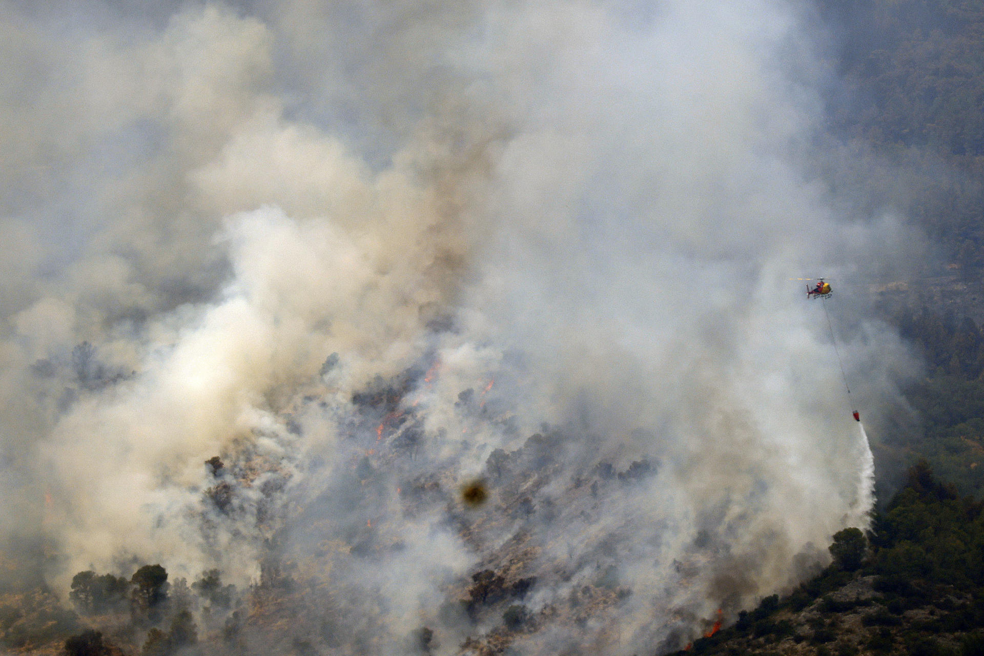 Un helicòpter en les feines per a apagar el foc a Alfara de Carles (fotografia: Quique Garcia).