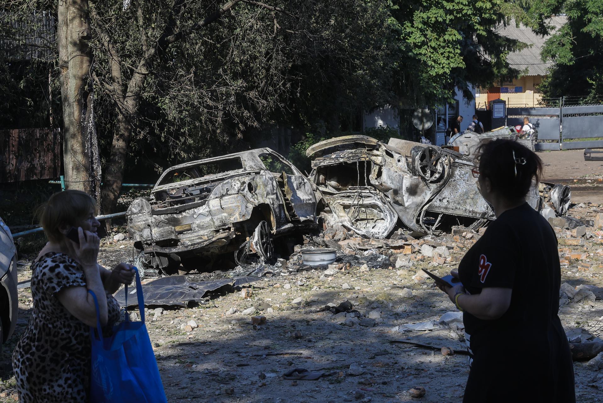 Veïns caminen per una zona afectada per un bombardeig rus a Kíiv, prop d’una escola i de vehicles destruïts. Fotografia: EFE/EPA/Sergey Dolzhenko.