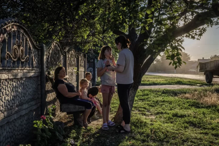 Svitlana Batiukh seu amb els seus néts –en Herman, de vuit anys, i la Miroslava, de quatre– i dos veïns al poble de Petrivka Druha, a la regió ucraïnesa de Donetsk. Insisteix que probablement hi romandrà encara que el poble sigui lliurat a Rússia (fotografia: Ed Ram/The Washington Post).