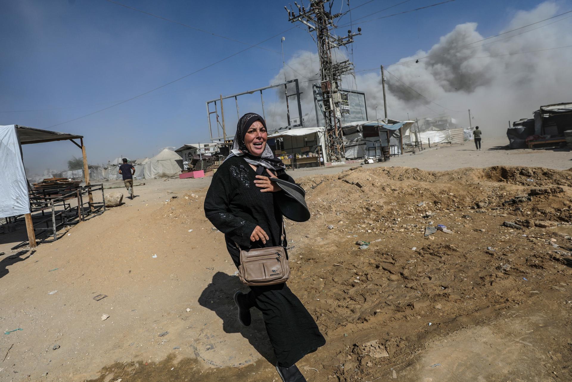 Una dona palestina corre a refugiar-se després d’un atac aeri israelià a l’oest de Gaza. Fotografia: EFE / Mohammed Saber.