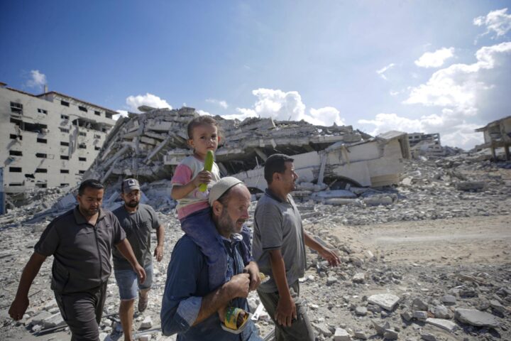 Una nena és carregada per un adult en un carrer de Gaza destruït per l'exèrcit israelià, l'octubre passat (fotografia: Ahmad Awad/Efe).
