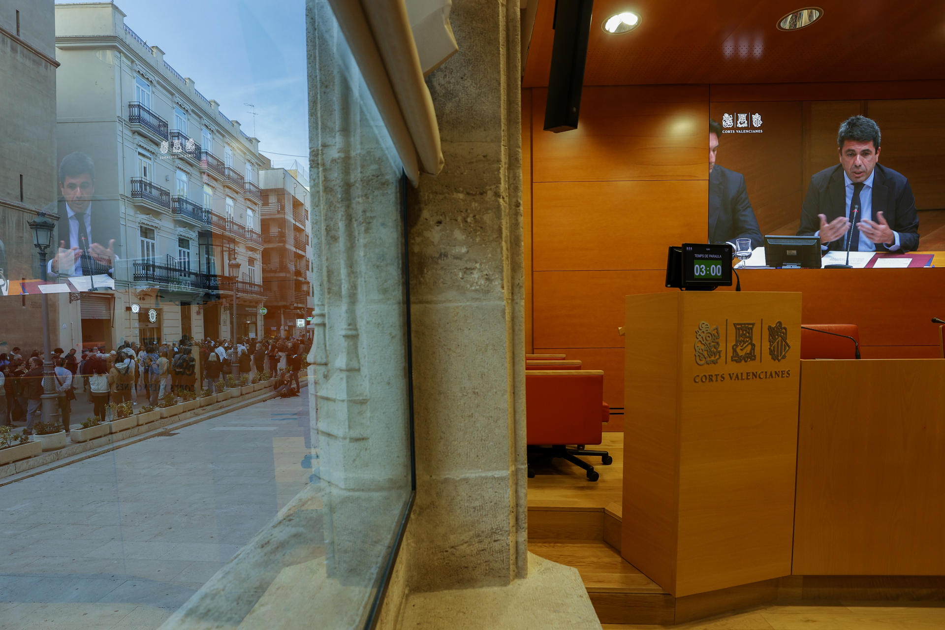 Una imatge de Carlos Mazón en la pantalla de la sala de premsa de les corts, dimarts passat, quan les associacions de víctimes es concentraven al carrer (fotografia: EFE / Manuel Bruque).