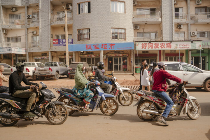 Motoristes passen per davant de cartells de botigues en xinès, al centre de Bamako, el mes passat (fotografia: Carmen Yasmine Abd Ali/The Washington Post).