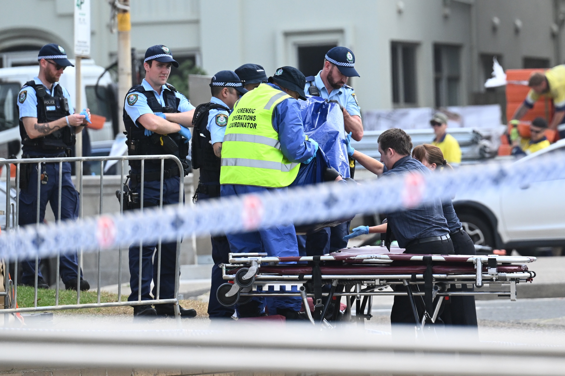 Forenses i agents de la policia retiren el cos d'una de les víctimes de l'atac a la platja Bondi de Sidney, abans-d'ahir (fotografia: Mick Tsikas/Efe).