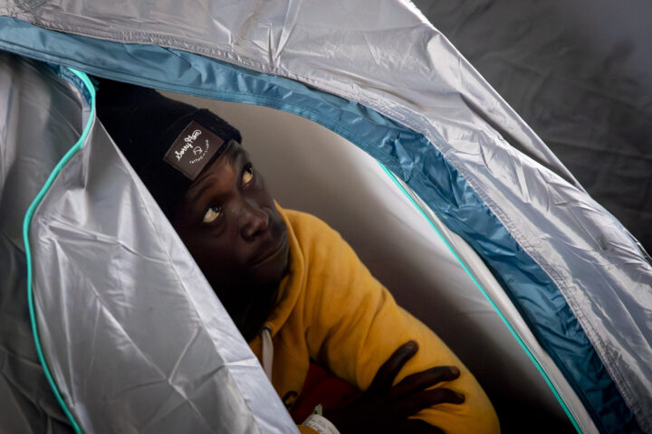 Una de les persones desallotjades a Badalona es refugia del fred i la pluja dins una tenda de campanya. Fotografia: Albert Salamé