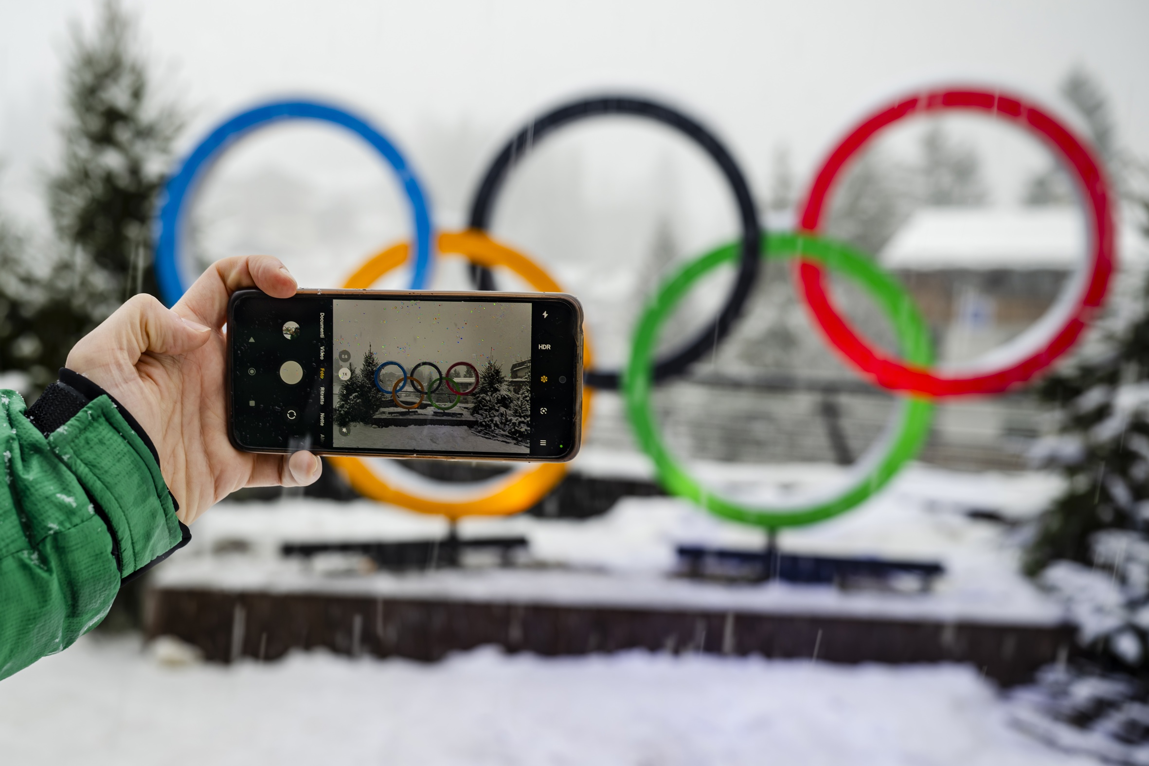 Un visitant fa una fotografia als anells olímpics a Cortina d'Ampezzo, una de les seus dels Jocs de Milà-Cortina, abans-d'ahir (fotografia: Jean-Christophe Bott/Efe).
