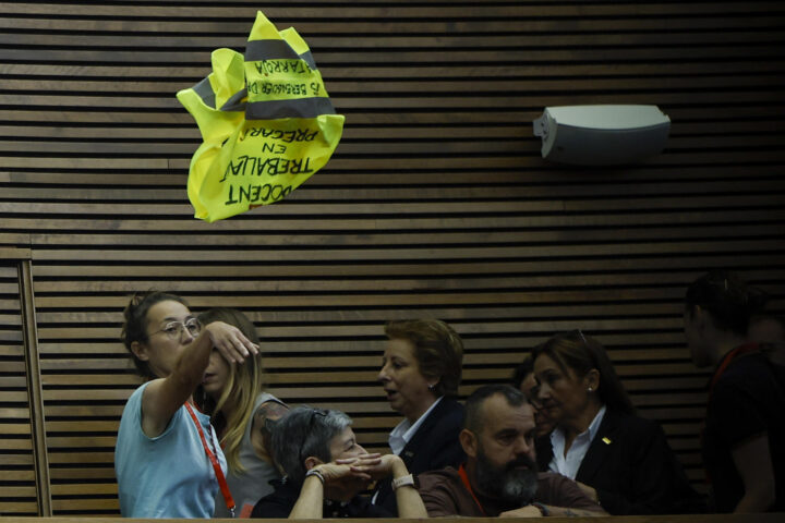 Una de les docents que ha interromput el ple llança una armilla amb la frase 