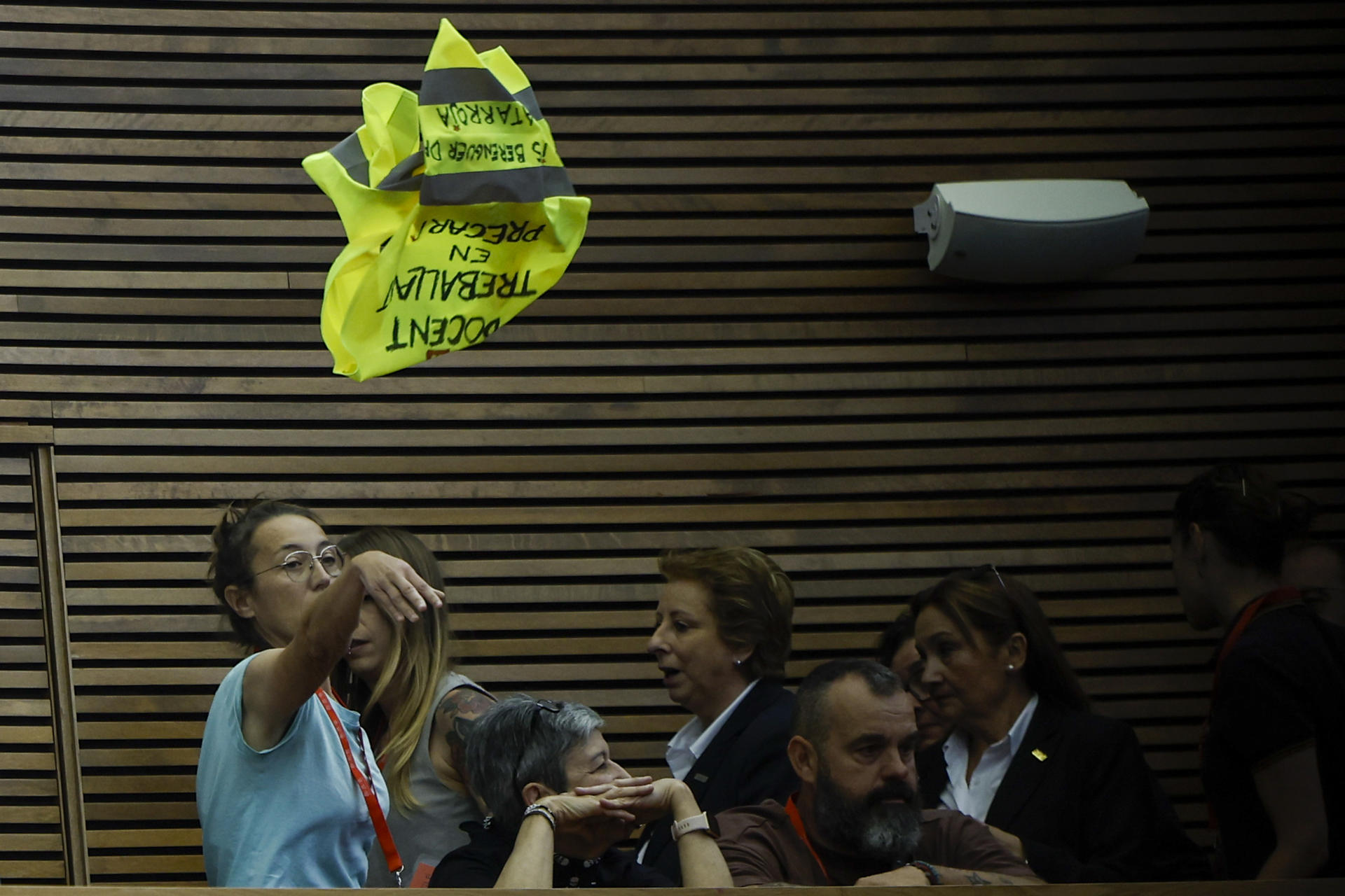 Una de les docents que ha interromput el ple llança una armilla amb la frase 